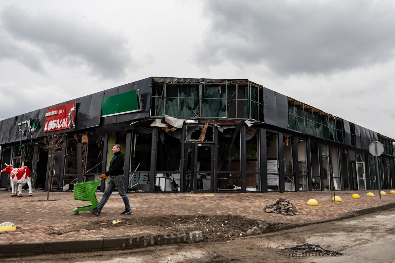 A person walks by a damaged building in Makariv, Kyiv Oblast, Ukraine, highlighting urban disaster impacts.