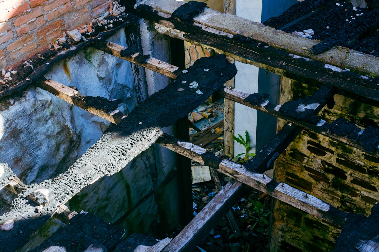 A top view of a charred wooden structure in a decaying, abandoned building showing signs of ruin.