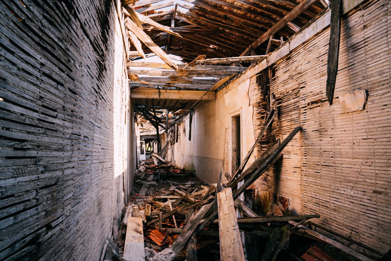 Explore the haunting interior of an abandoned building with a collapsed roof and debris-filled hallway.