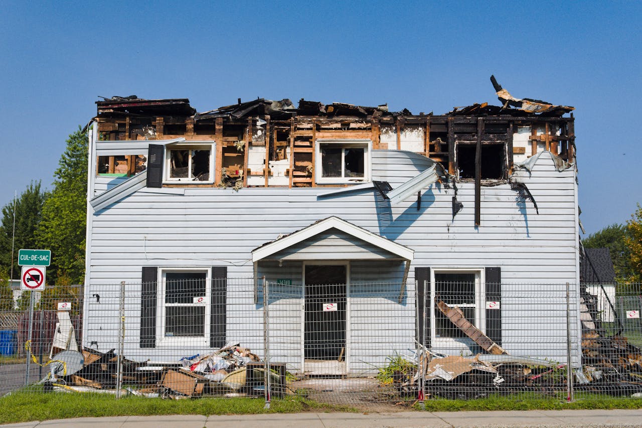 A damaged house with a burnt roof in Bécancour, Quebec, surrounded by a fence.
