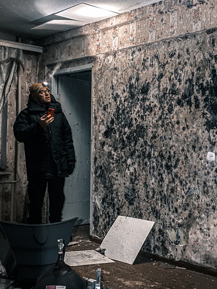 Man with flashlight inspects mold-covered walls in an abandoned building in Vorkuta, Russia.