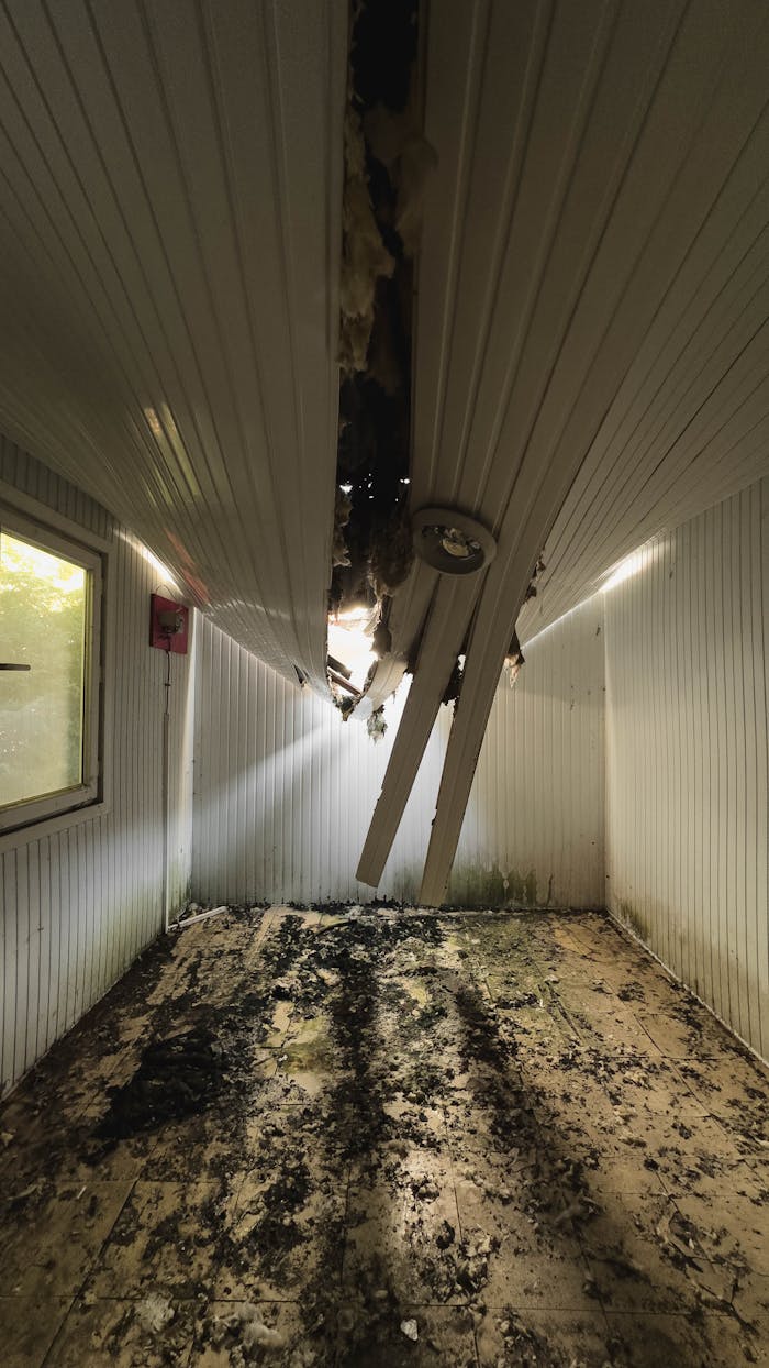 Interior of a room with a collapsed ceiling showing damage and debris.